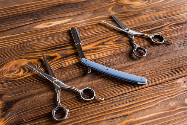 Close-up of razor and scissors on wooden table