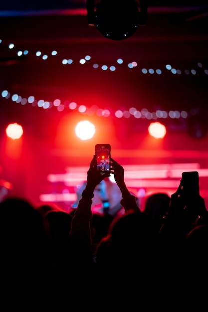 コンサート中にスマートフォンでビデオを録画するクローズアップ。トーンの写真