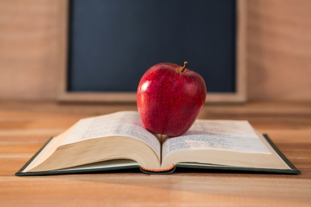 Close up of red apple with open book