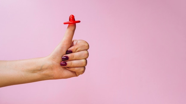 Free photo close-up red condom on the thumb