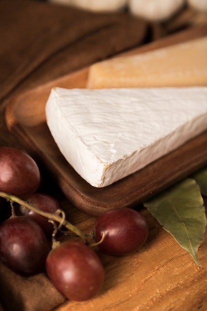 Foto gratuita close-up di uva rossa e fette di formaggio sul piatto di legno