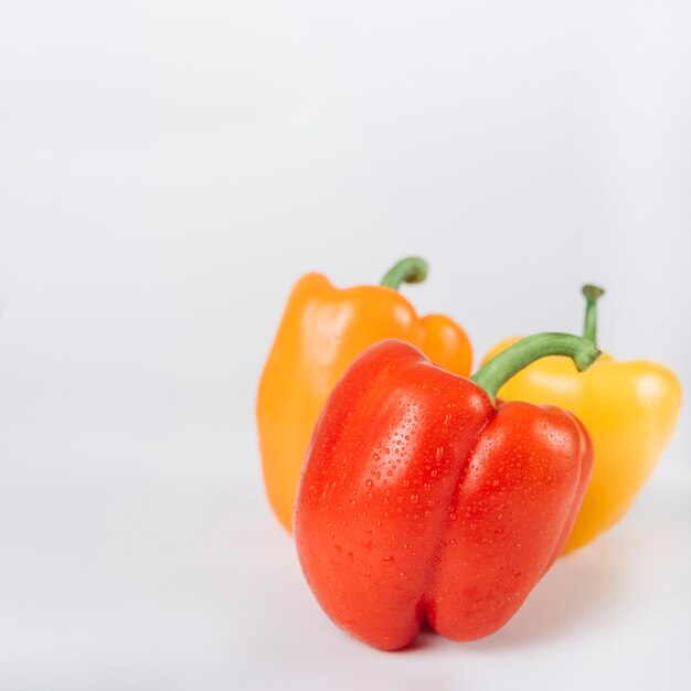 Close-up of red; orange and yellow bell peppers on white backdrop