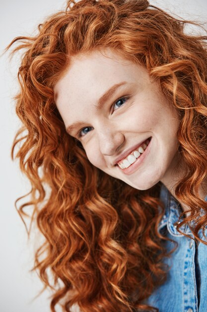 Close up of redhead beautiful girl with freckles smiling .
