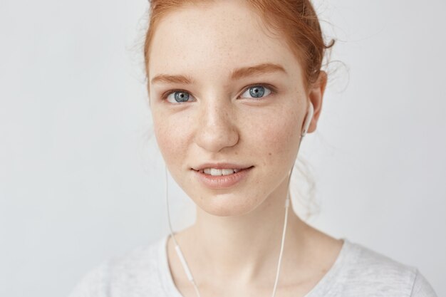 Close up of redhead woman in headphones smiling.