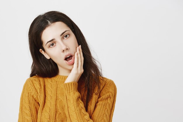 Close-up of reluctant and bored girl yawning, looking unamused