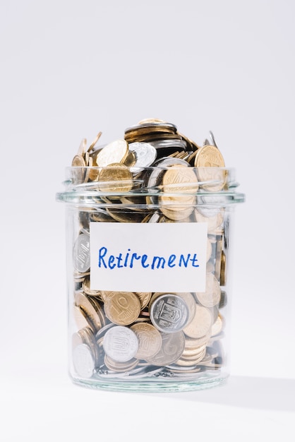 Close-up of retirement glass container full of coins on white background