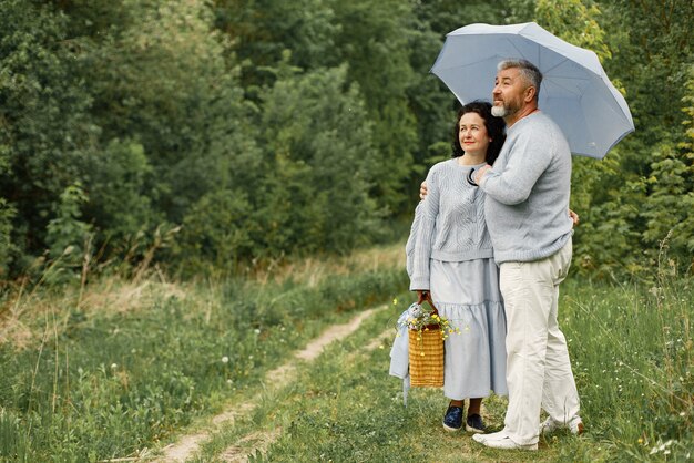 Close up romantic couple standing in autumn park under umbrella in daytime