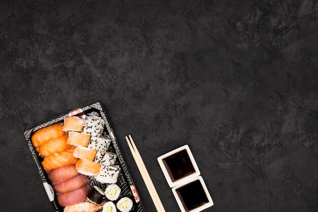 Close-up of sashimi sushi on plate with soya sauce over black surface