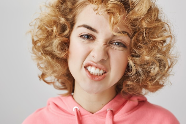 Close-up of sassy happy girl showing teeth, grimacing