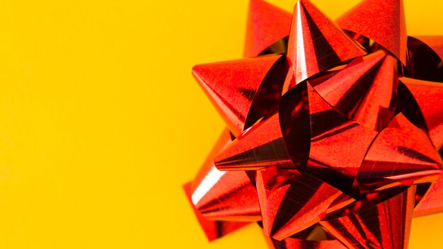 Close-up of satin red ribbon bow on yellow background