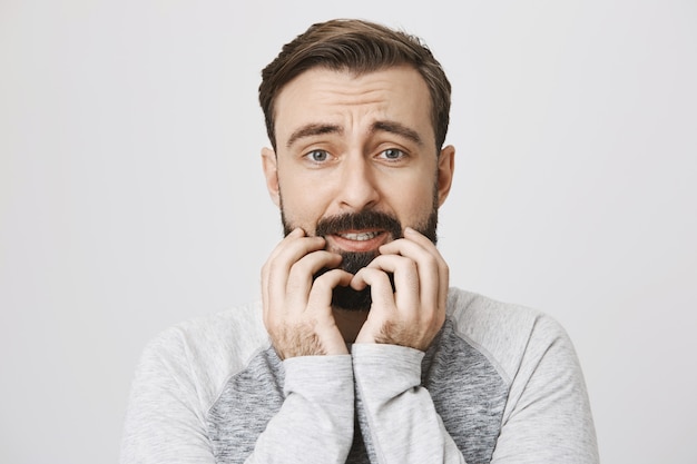 Close-up of scared bearded guy looking anxious and alarmed