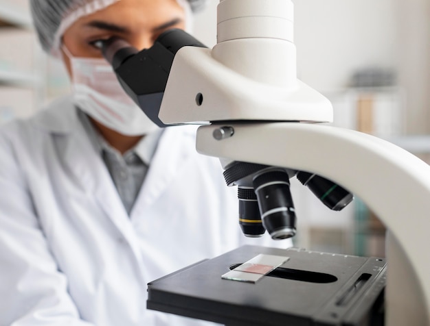 Free photo close up scientist looking at glass slide