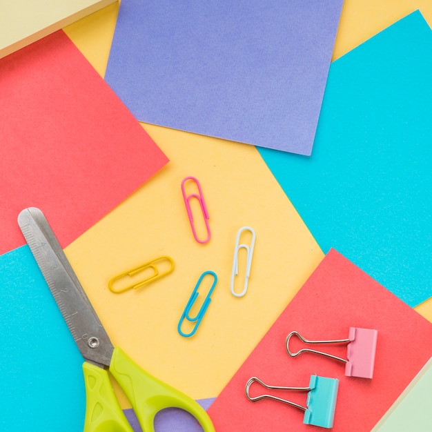 Close-up of scissor; paper clip and colorful sticky note