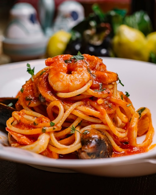 Крупным планом спагетти с морепродуктами, томатным соусом с мидиями и креветками и петрушкой