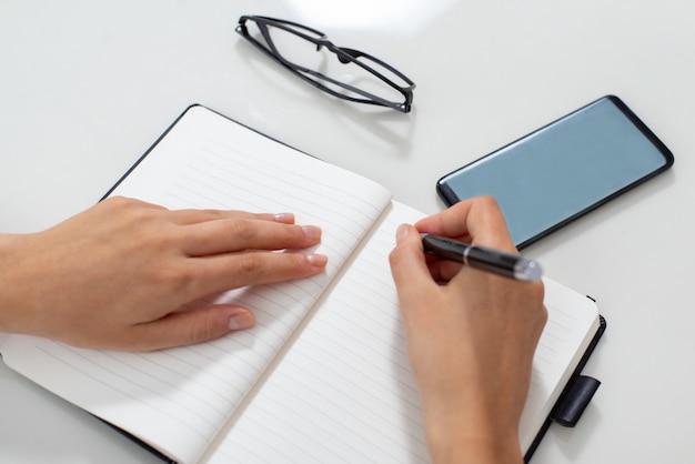 Close-up of secretary hands writing down appointment in notebook