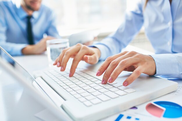 Close-up of secretary typing on laptop