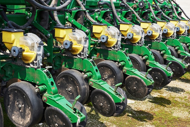 Close up of seeder attached to tractor in field.