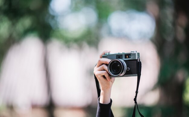 クローズアップと選択的な焦点自然の森のコピースペースでスナップショットを撮るためにデジタルカメラを持っている女性のプロの写真家の手