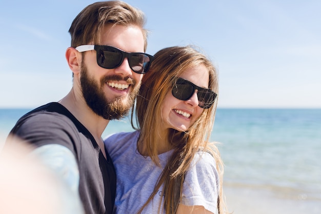 Close-up self-portrait of young couple standing near sea