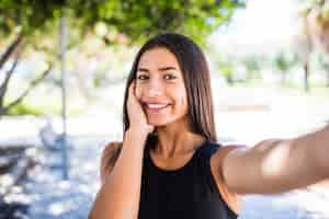 Free photo close up selfie portrait smiling latin young woman outside