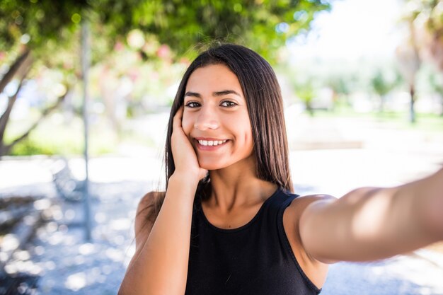 Крупным планом селфи портрет улыбающейся латинской молодой женщины снаружи