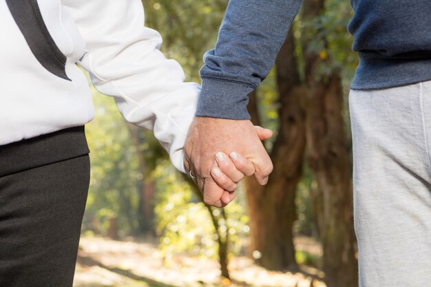 Close-up of senior couple holding hands and walking in the forest