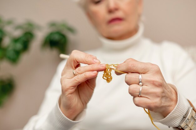Close-up senior female knitting at home