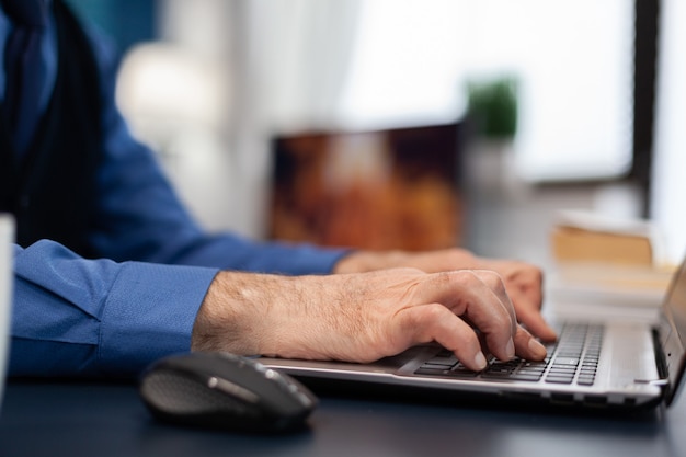 Close up of senior man hands typing