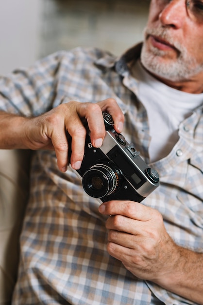 Close-up of senior man holding camera in hand