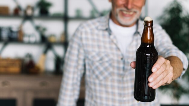 Close-up of senior man offering beer bottle