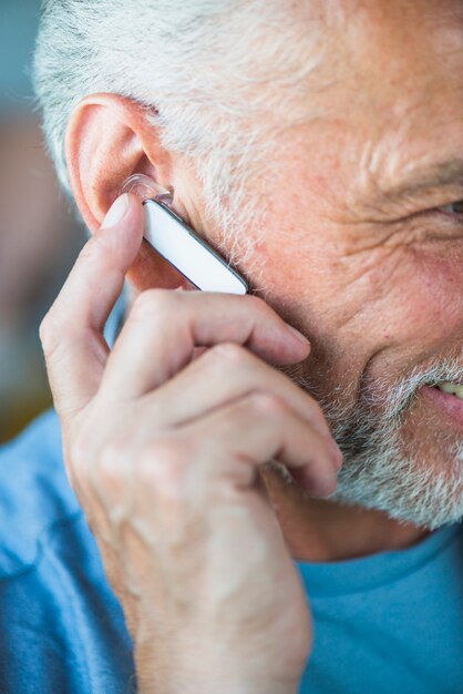 Close-up of senior man's hand on bluetooth headset on his ear