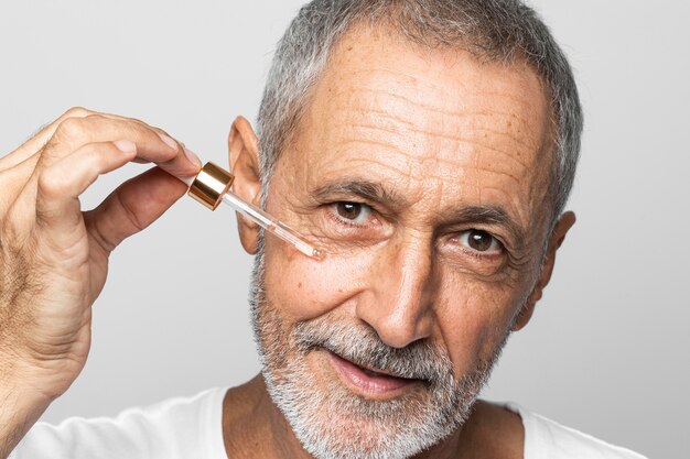 Close-up senior man using serum