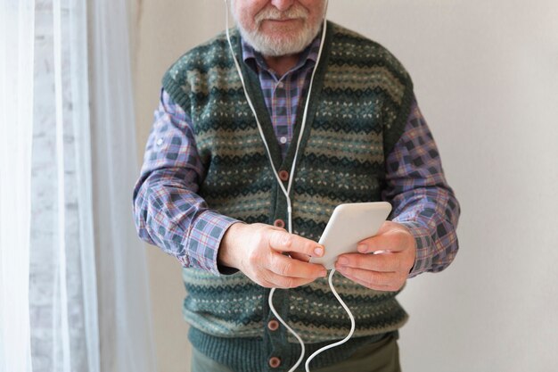 Бесплатное фото Крупным планом старший играет музыку на мобильном телефоне