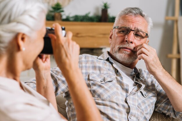 Close-up of senior woman taking picture of her husband from camera