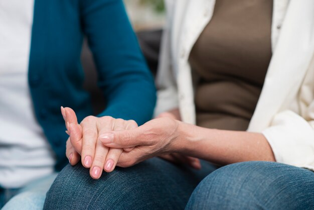 Close-up senior women holding hands