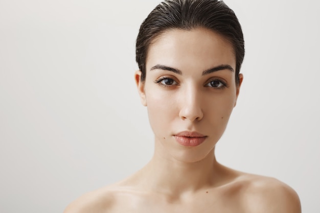 Close-up of sensual young woman standing naked shoulders and gazing