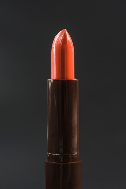 Close-up of shiny red lipstick against black backdrop