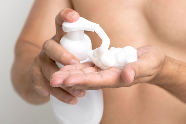 Close up of shirtless man pouring shaving foam on his hand