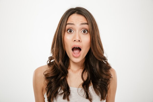 Close up Shocked brunette woman looking at the camera with open mouth over gray