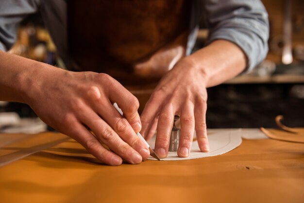 Close up of a shoemaker cutting leather