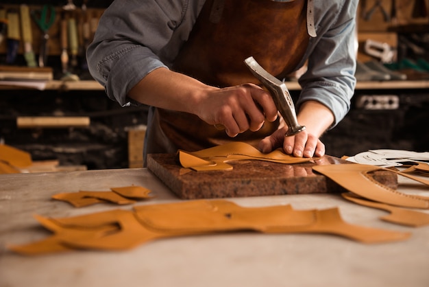 Close up of a shoemaker man working with leather