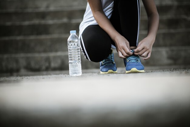 靴を閉じますジョギングの運動のために彼女の靴を結ぶ女性ランナー