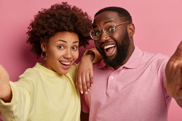 Close up shot of Afro American couple or friends extend hands and make selfie