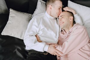 Close up shot of appealing happy gay couple smiling. resting in bed.