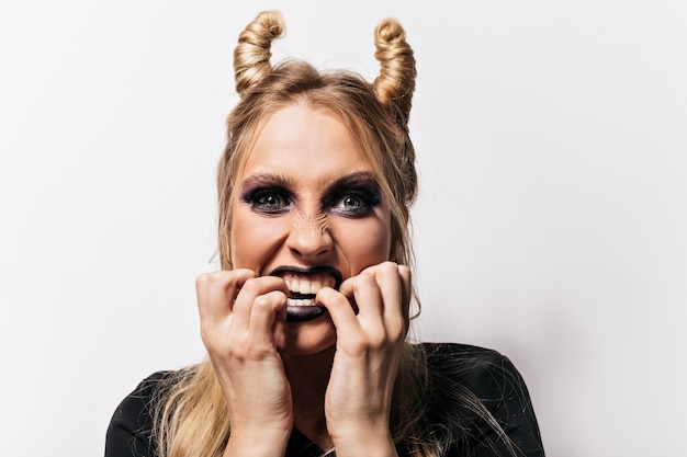 Free photo close-up shot of appealing little witch. portrait of happy woman in vampire costume posing in halloween.