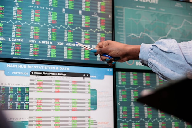 Close up shot of brokerage company employee indicating on display real time profit growth and market trend. Hedge fund agency trader pointing out positive market trend on professional display.