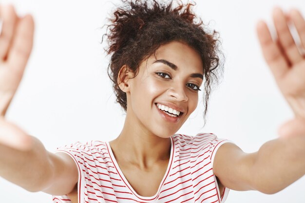 Close-up shot of carefree friendly woman with afro hairstyle posing in the studio