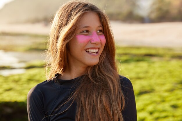 Close up shot of cheerful Caucasian female likes surfing