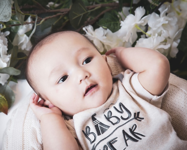 Free photo close up shot of a cute caucasian baby boy surrounded by flowers