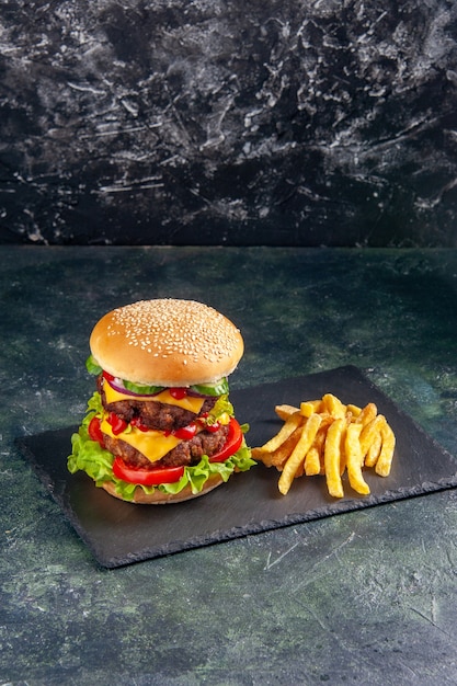Close up shot of delicious sandwich and fries on dark color tray on black surface